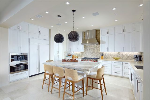 a kitchen with stainless steel appliances kitchen island granite countertop a stove a refrigerator a oven a sink with a dining table and chairs