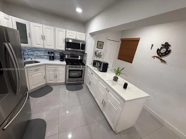 a kitchen with white cabinets and stainless steel appliances