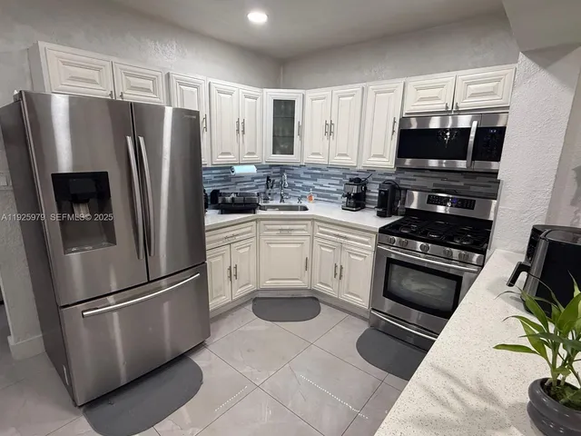 a kitchen with stainless steel appliances a refrigerator sink and microwave