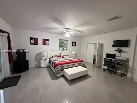 a spacious bedroom with a bed and a flat screen tv