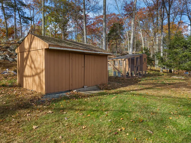a view of a barn house next to a yard with wooden fence
