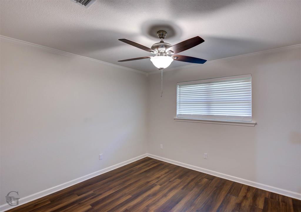 207 Chimney Lane Haughton, LA 71037 - Photo 12 of 18 Empty room with dark wood-style floors, ceiling fan, and ornamental molding