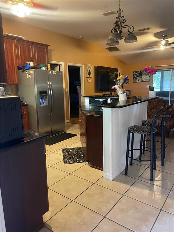 396 Kettering Road Deltona, FL 32725 - Photo 12 of 25 a kitchen with stainless steel appliances kitchen island granite countertop a refrigerator and a stove top oven