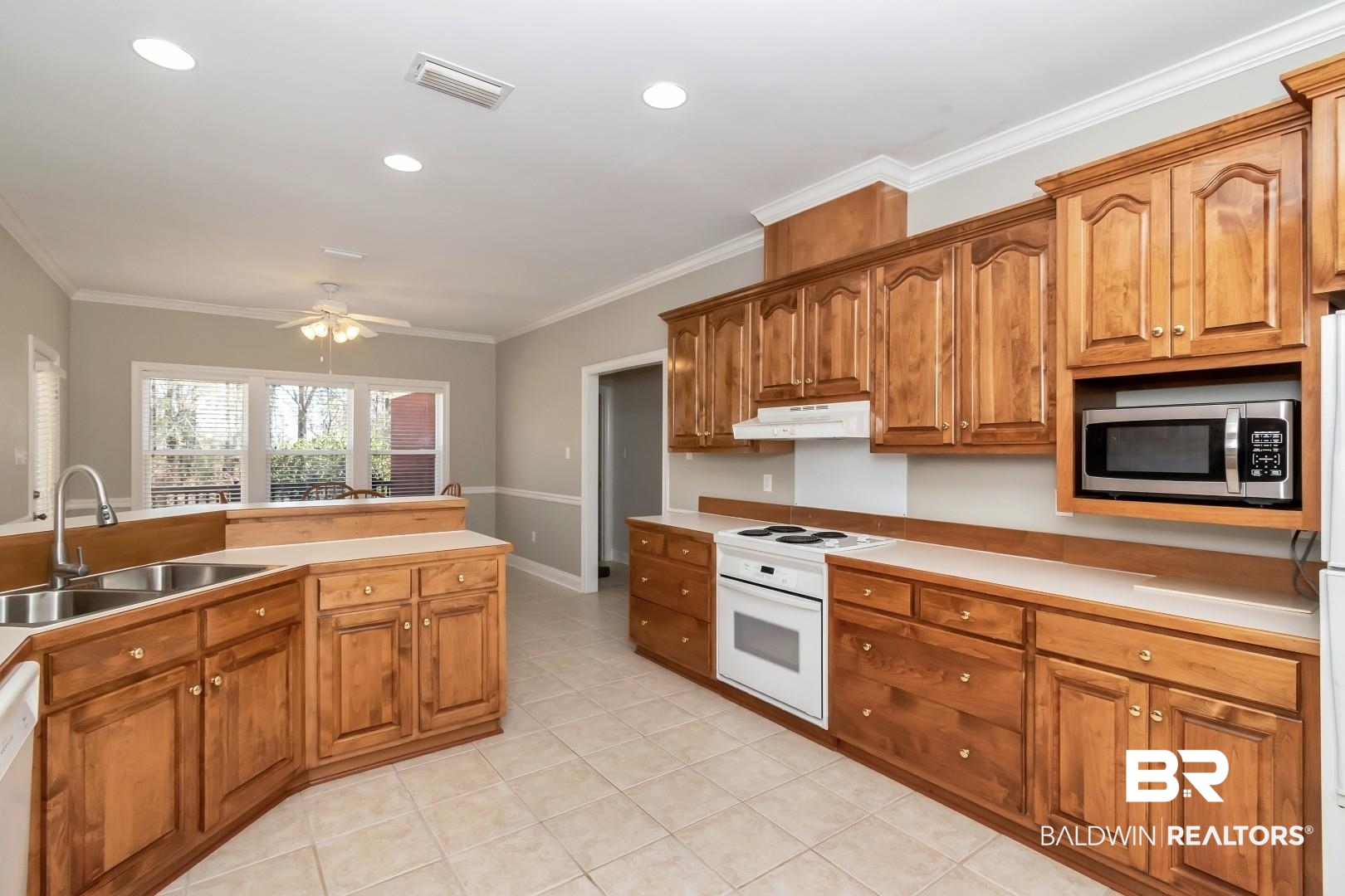 6090 Celeste Road Saraland, AL 36571 - Photo 12 of 38 Kitchen with white appliances, under cabinet range hood, a sink, ceiling fan, and visible vents