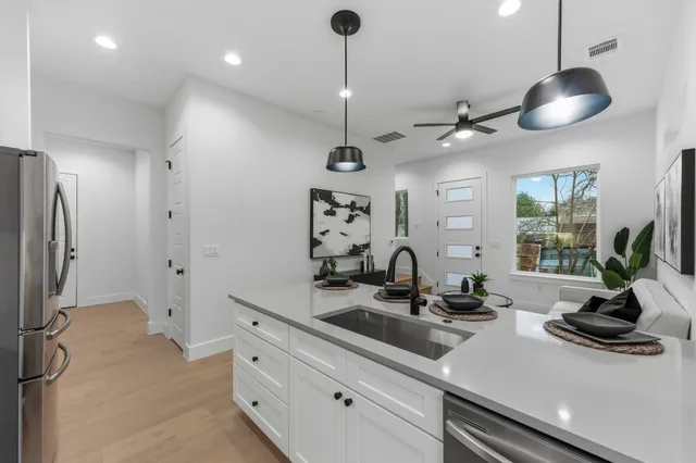 a kitchen with stainless steel appliances a counter space a sink a refrigerator and a window