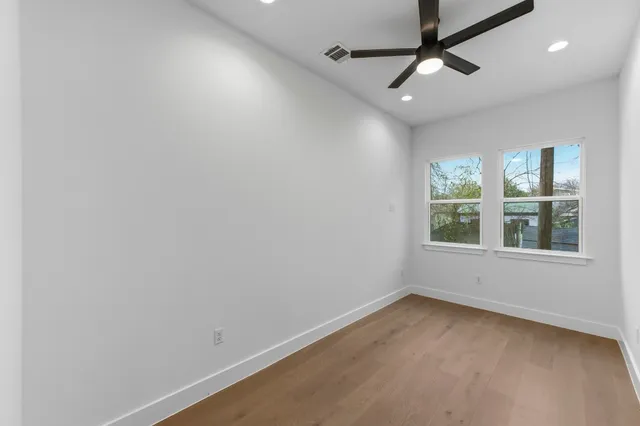 an empty room with a window and ceiling fan