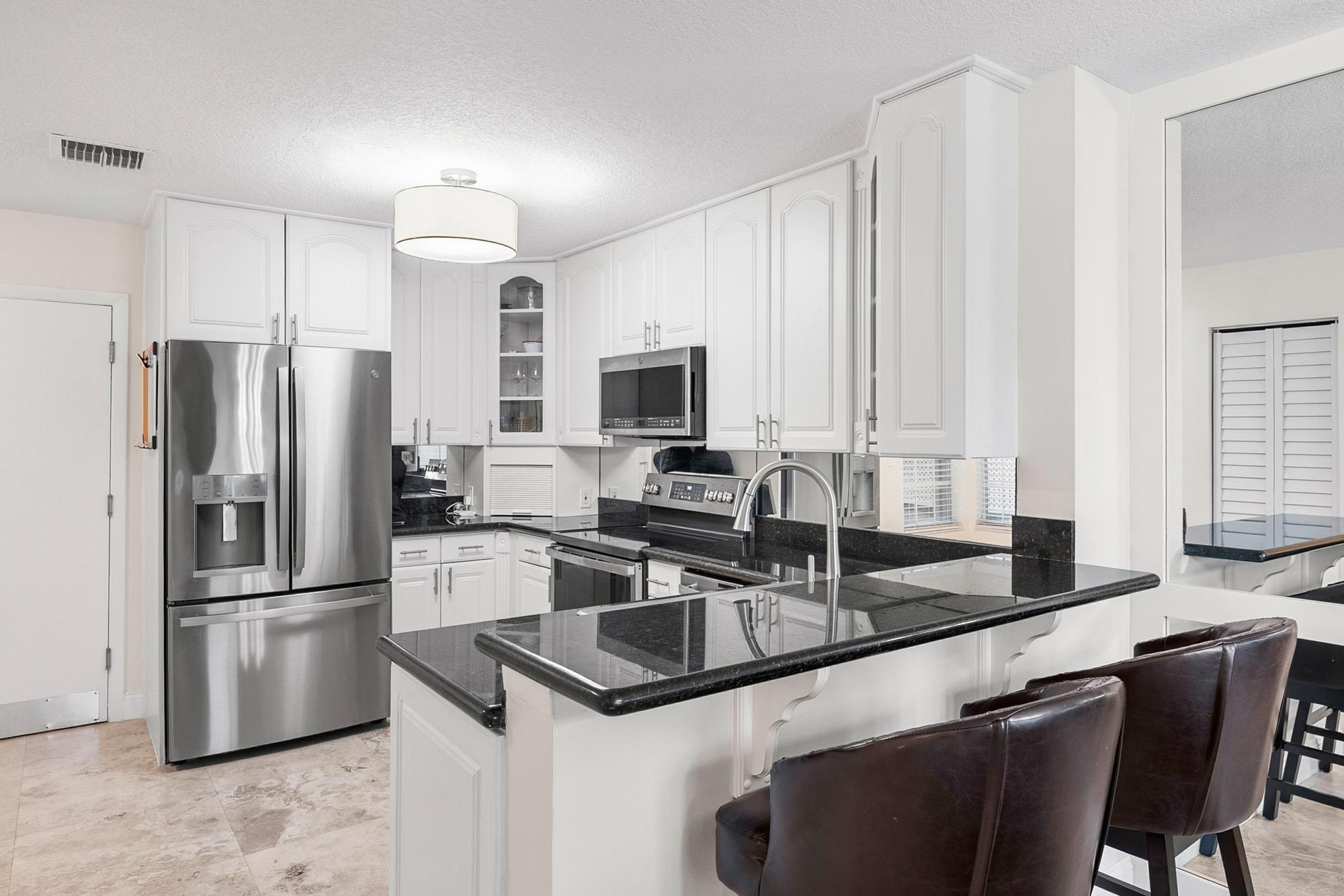 1219 Ocean Dunes Circle Jupiter, FL 33477 - Photo 25 of 35 a kitchen with stainless steel appliances granite countertop a sink refrigerator and microwave