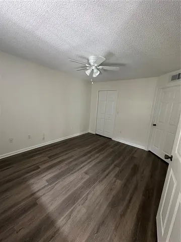 an empty room with wooden floor and fan