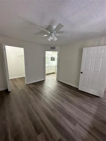 an empty room with wooden floor and ceiling fan