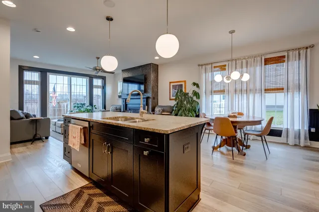 a kitchen with a stove a sink a dining table and chairs with wooden floor
