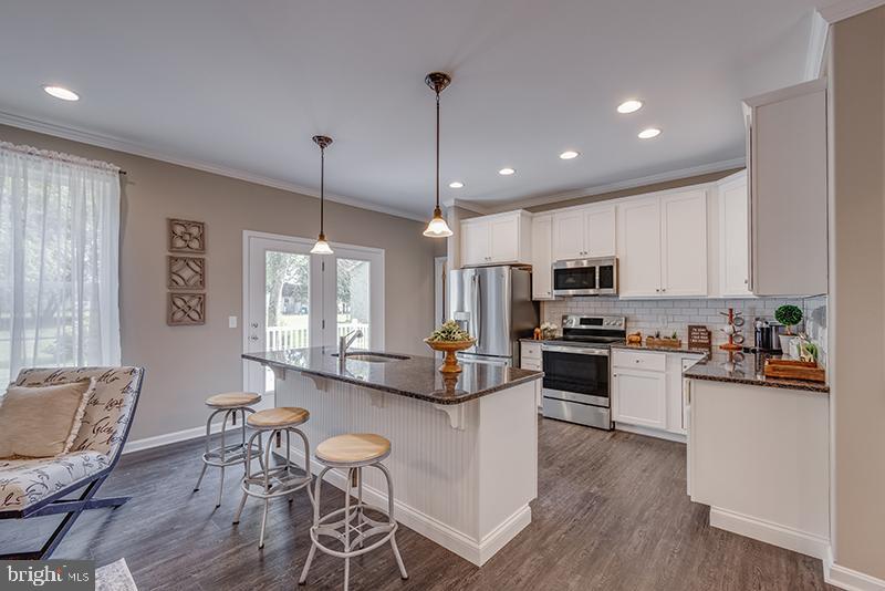 38 High Ridge Road Felton, DE 19943 - Photo 43 of 51 a kitchen with stainless steel appliances kitchen island granite countertop a stove a refrigerator a kitchen island a dining table and chairs with wooden floor
