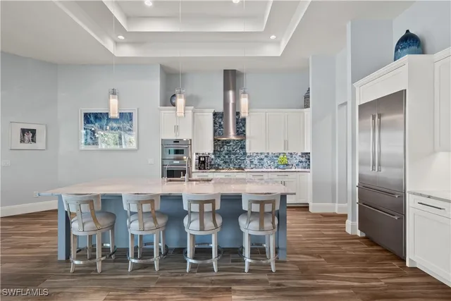 a kitchen with stainless steel appliances a dining table chairs and wooden floor