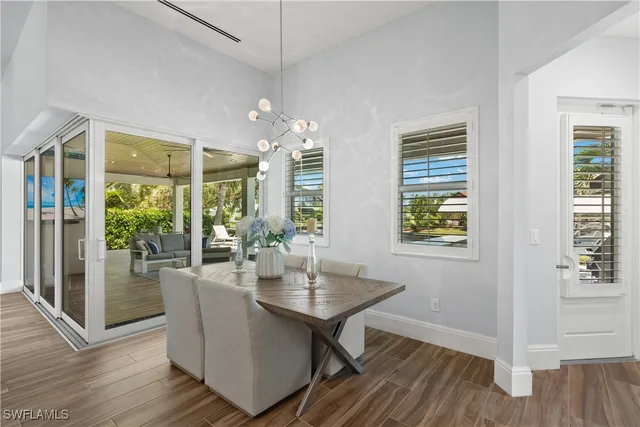 a dining room with wooden floor a chandelier a glass table and chairs