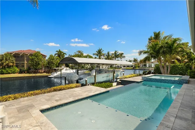 a view of a swimming pool with lawn chairs plants and palm trees