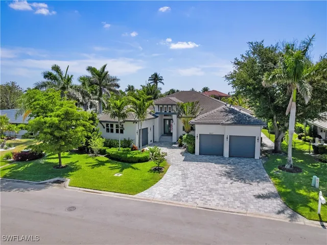 a front view of a house with a garden and trees