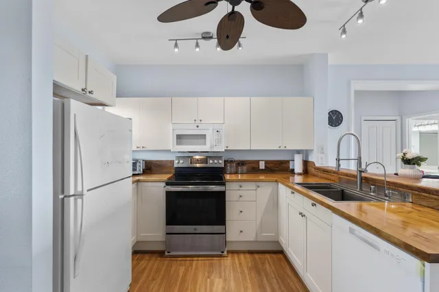 a kitchen with stainless steel appliances a refrigerator a sink and wooden floors