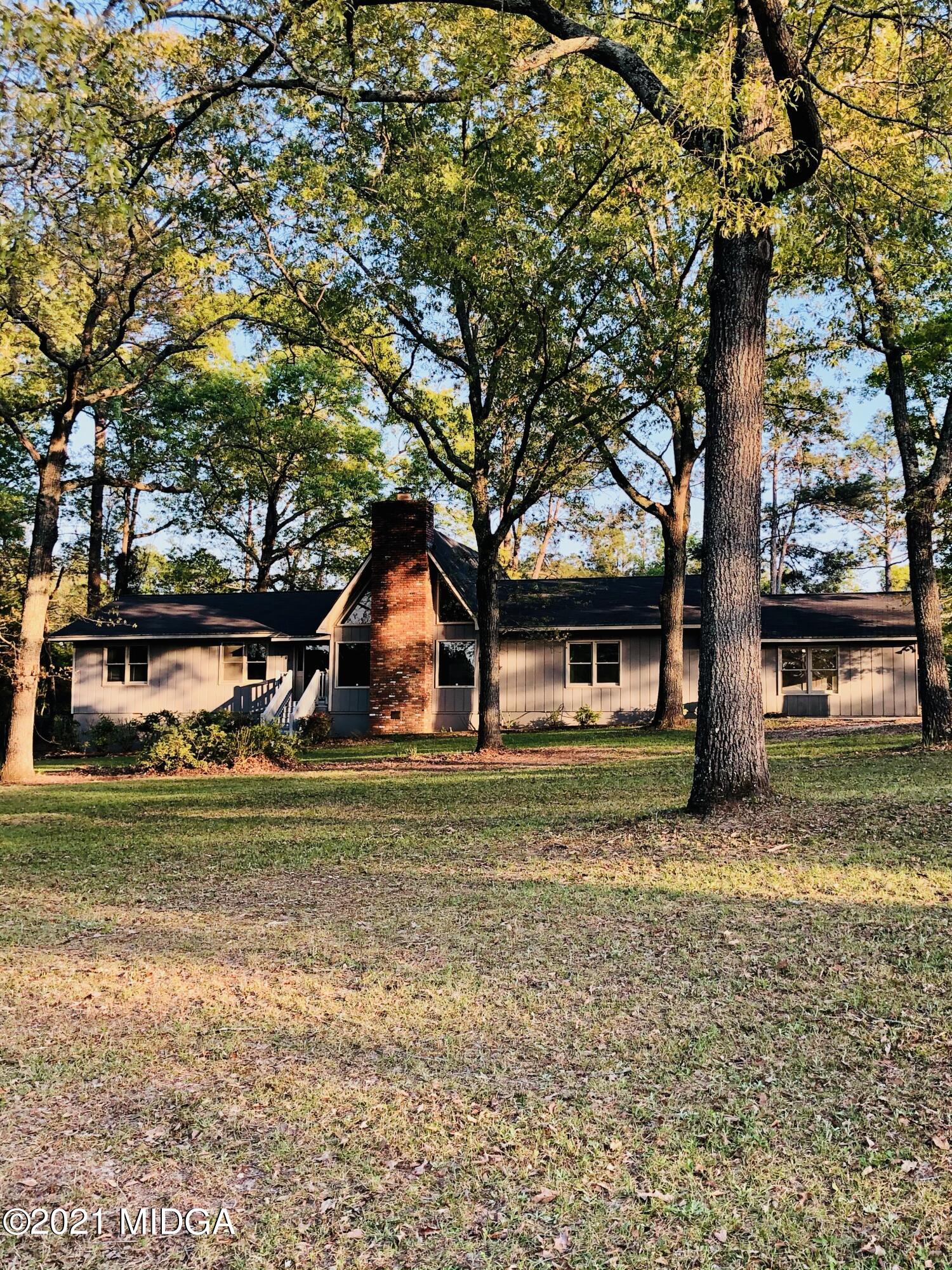 a front view of a house with a garden and trees
