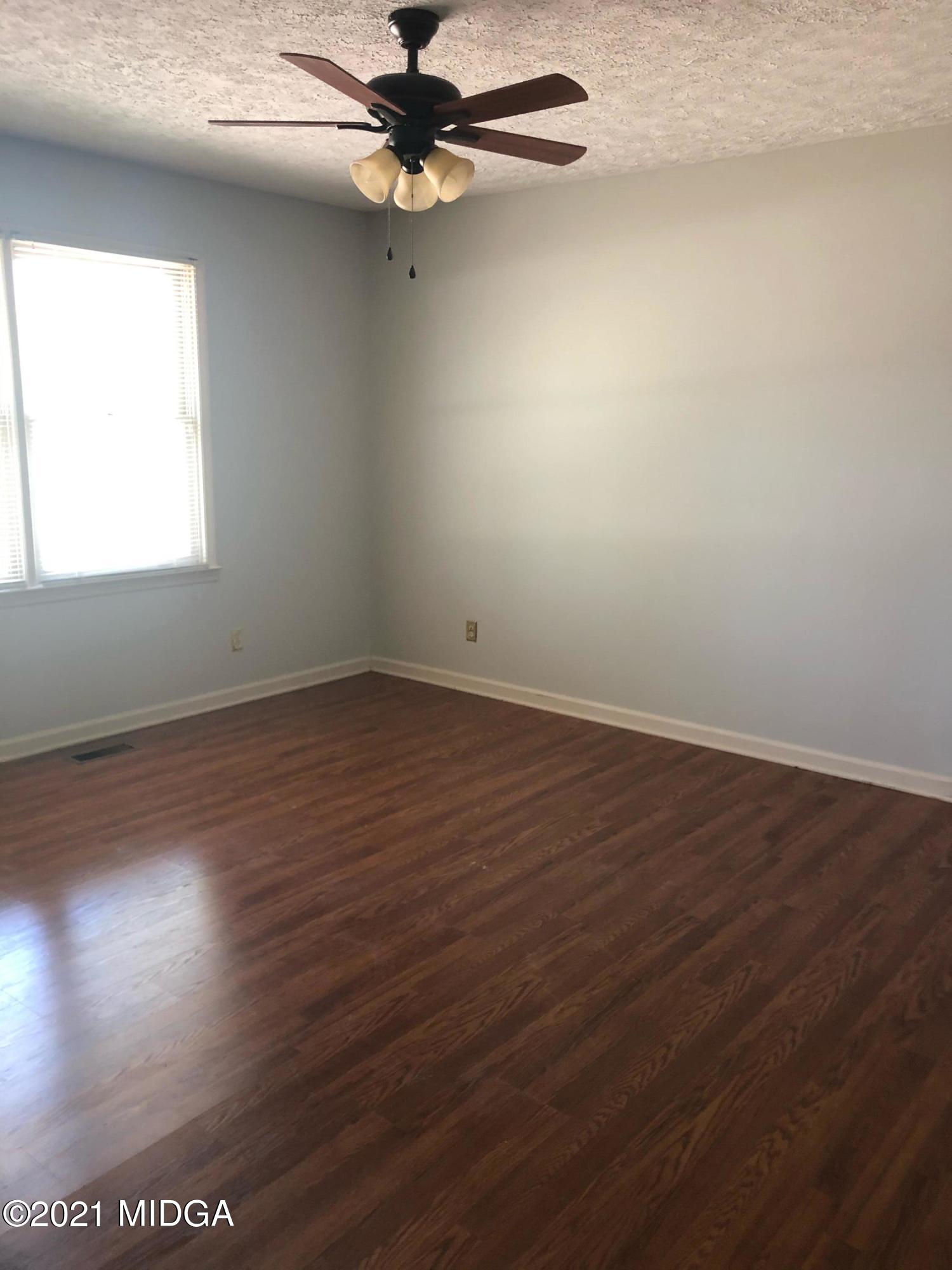 4980 Dixon Road Lizella, GA 31052 - Photo 9 of 10 an empty room with wooden floor fan and windows