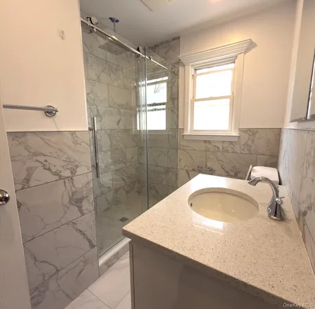a bathroom with a granite countertop sink a window and shower
