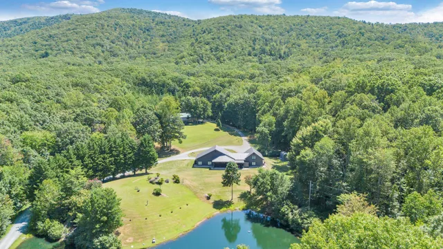 an aerial view of residential house with outdoor space and trees all around
