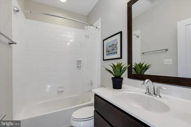 a bathroom with a granite countertop sink a toilet and shower