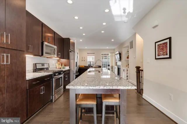 a large kitchen with stainless steel appliances granite countertop a stove refrigerator and a sink