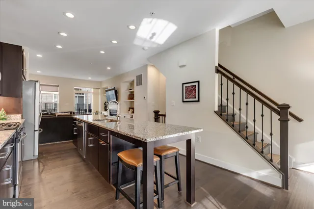 a kitchen with stainless steel appliances kitchen island granite countertop a dining table and chairs