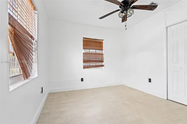 an empty room with a window and a fan