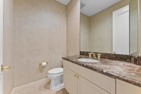 a bathroom with a granite countertop sink a toilet and a mirror