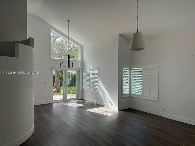 a view of an entryway with wooden floor windows and a ceiling fan