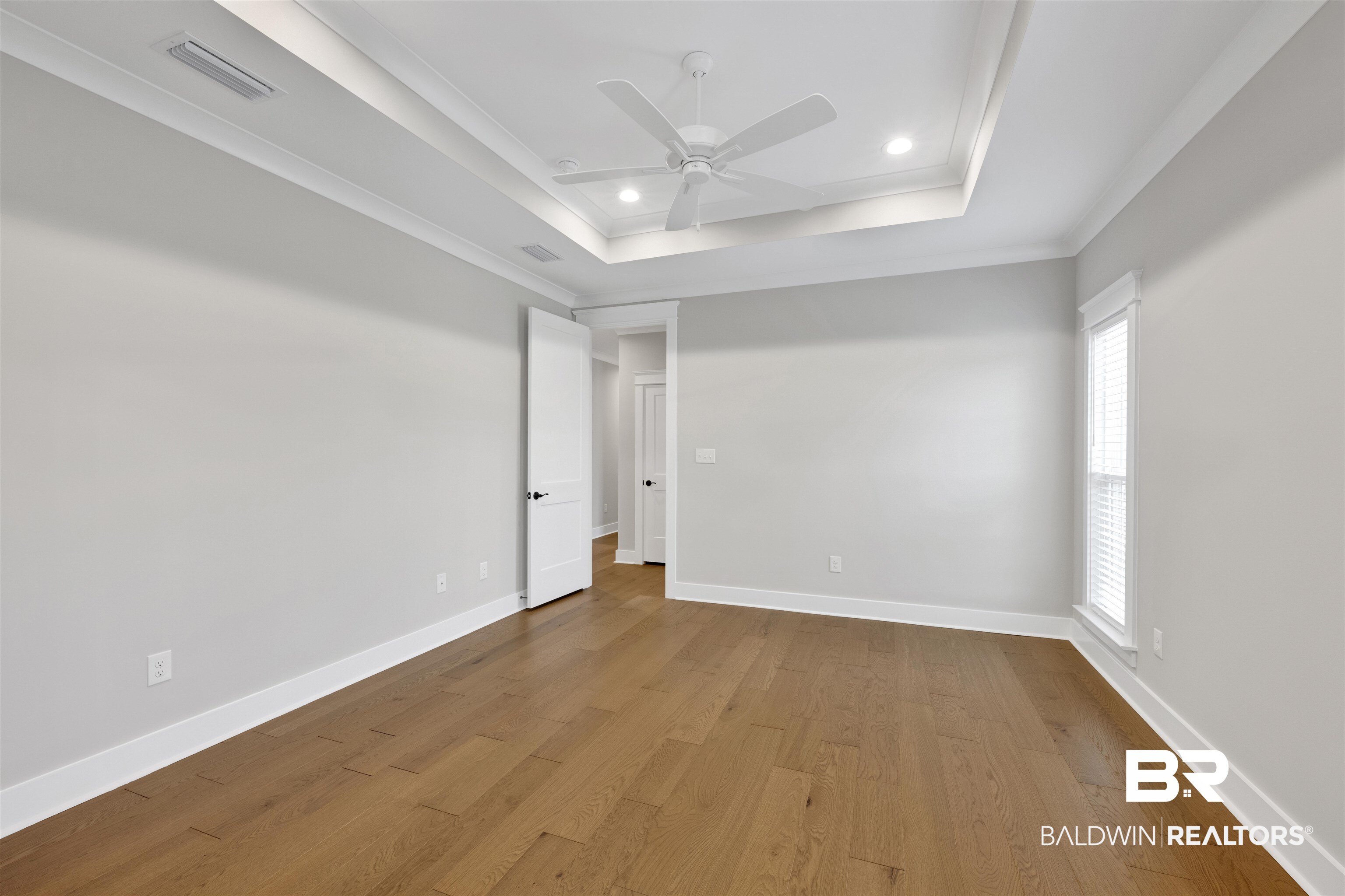 27371 Patch Pl Loop Daphne, AL 36526 - Photo 53 of 63 Spacious room featuring wood-finish flooring, a tray ceiling with recessed lighting, an overhead ceiling fan, white baseboards, and a window with blinds