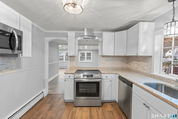 a kitchen with cabinets wooden floor and stainless steel appliances