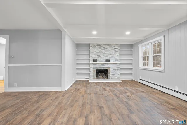 a view of empty room with wooden floor and fireplace