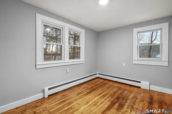 a view of empty room with wooden floor and fan