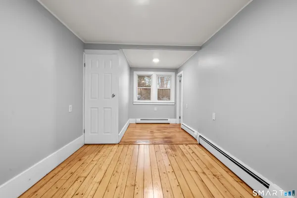a view of empty room with wooden floor and fan
