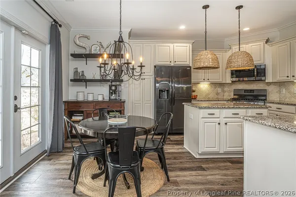 a kitchen with stainless steel appliances granite countertop a stove a refrigerator a kitchen island a dining table and chairs