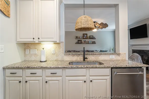 a kitchen with stainless steel appliances granite countertop a sink a stove and a white cabinets with wooden floor