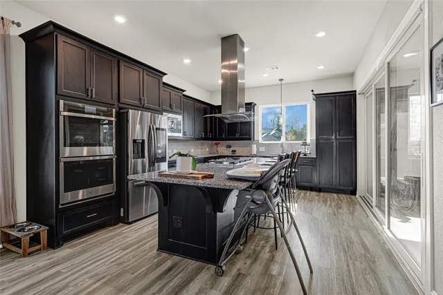 a kitchen with stainless steel appliances a kitchen island hardwood floor sink stove dining table and chairs