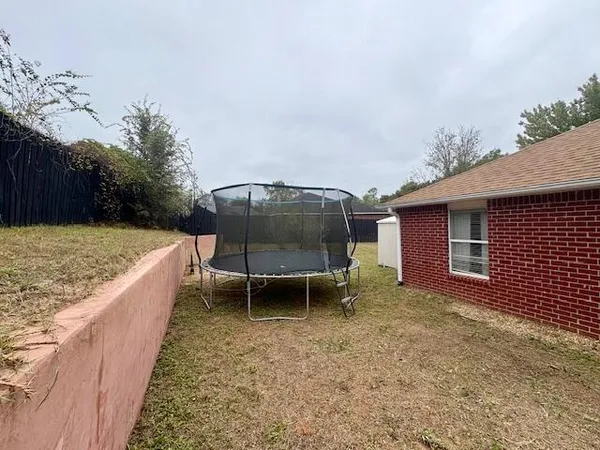 a backyard of a house with yard and trampoline