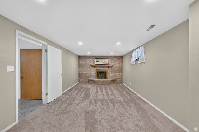 4468 North Droubay Road Tooele, UT 84074 - Photo 32 of 60 Recessed lighting throughout, brick fireplace with raised hearth, light-toned carpeting, neutral wall paint, and white trim