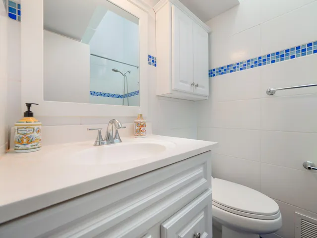 a large kitchen with granite countertop a sink dishwasher a stove and white cabinets with wooden floor