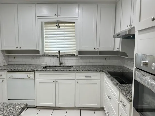 a kitchen with granite countertop white cabinets and stainless steel appliances