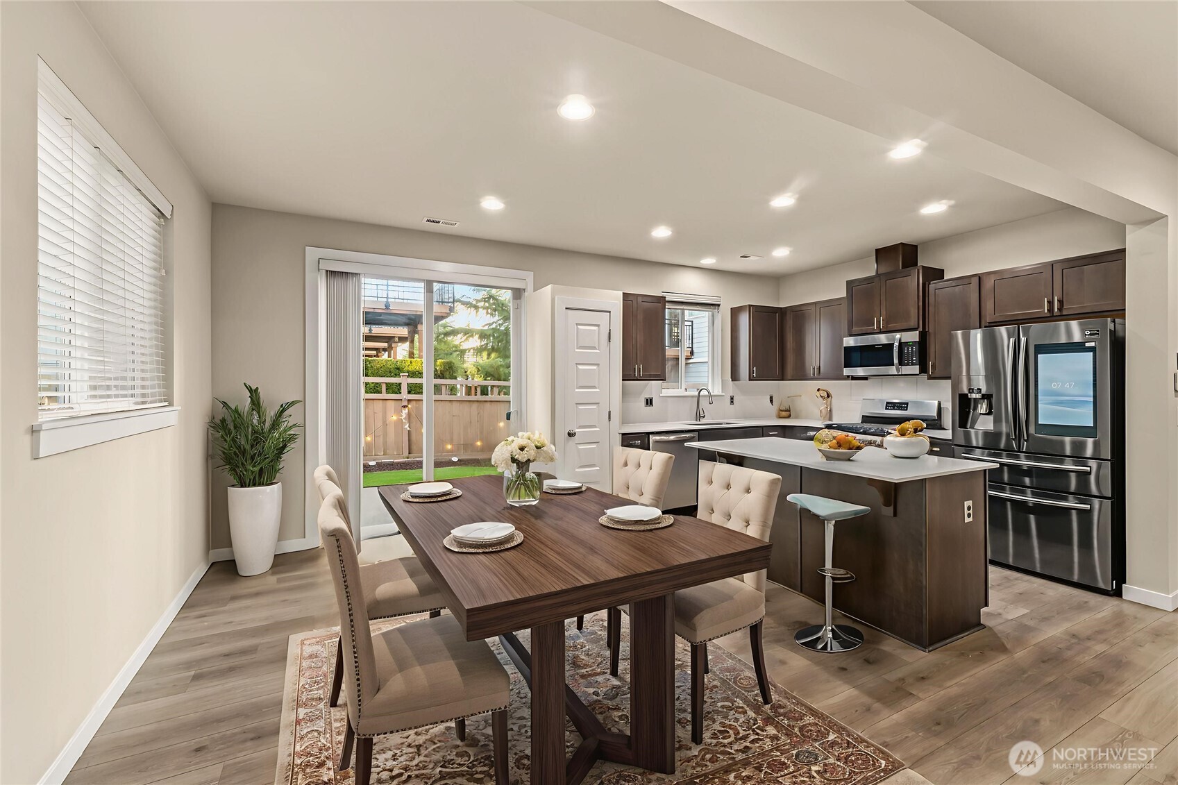 19326 37th Avenue Southeast, Unit C Bothell, WA 98012 - Photo 6 of 32 a kitchen with stainless steel appliances granite countertop a stove top oven a sink dishwasher a dining table and chairs with wooden floor