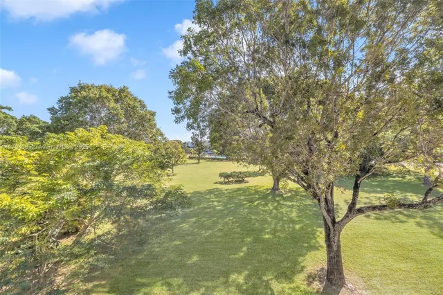 a view of a house with a big yard and large trees