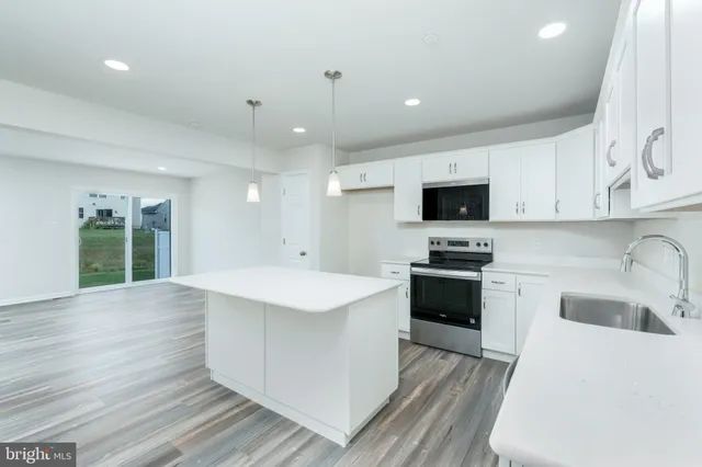 a kitchen with a sink a stove top oven and white cabinets