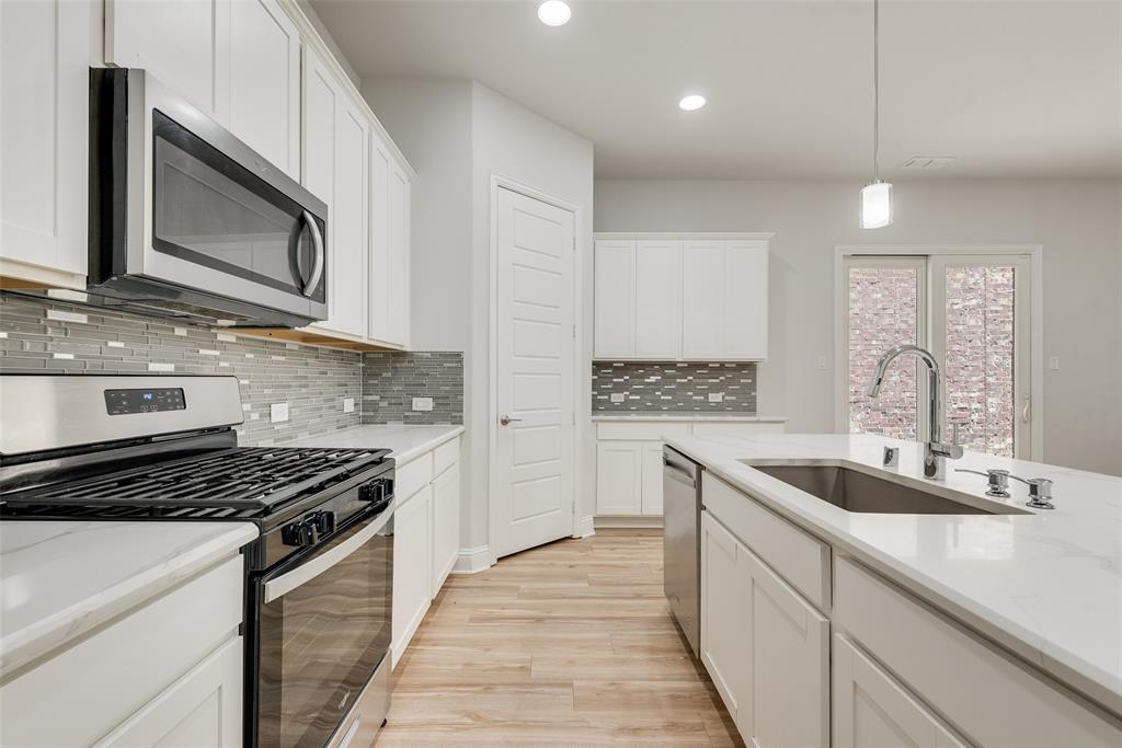 628 Ansley Way Allen, TX 75013 - Photo 6 of 20 Modern kitchen featuring white cabinetry, light-toned wood-finish flooring, and a stone-look countertop