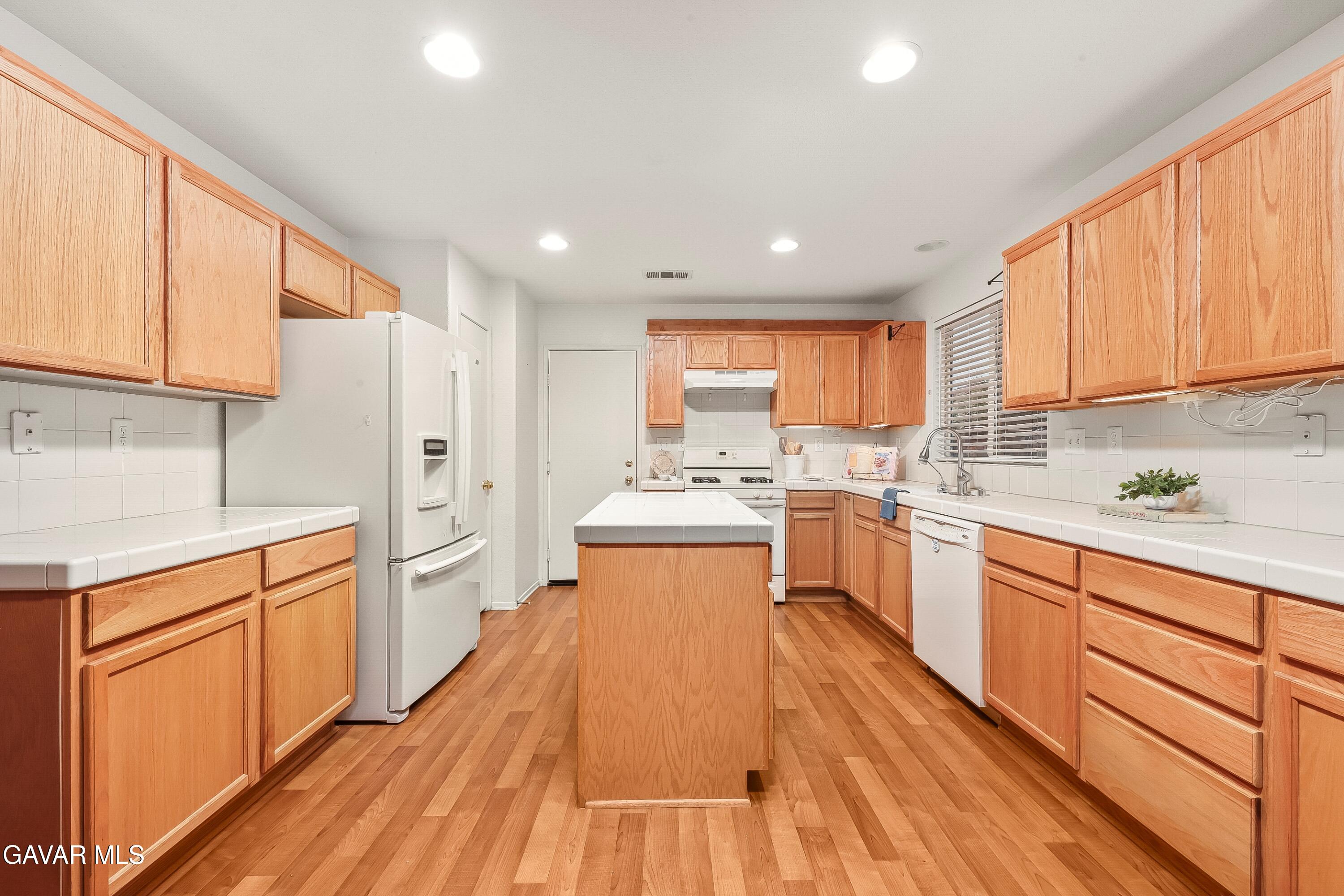 43635 Castle Circle Lancaster, CA 93535 - Photo 31 of 53 a open kitchen with stainless steel appliances granite countertop a stove top oven a sink dishwasher and a refrigerator with wooden floor