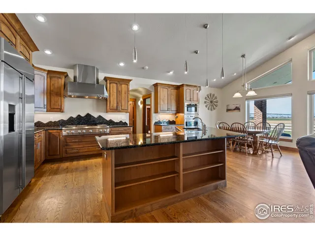 a kitchen with stainless steel appliances kitchen island granite countertop a stove and a view of living room