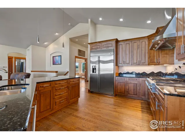 a kitchen with stainless steel appliances granite countertop a sink a stove and a refrigerator