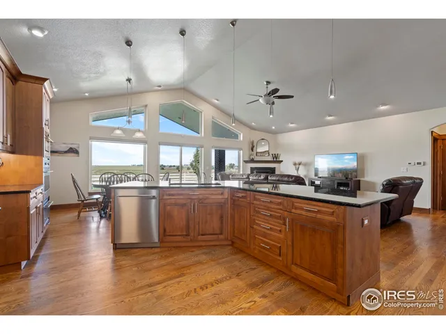 a kitchen with stainless steel appliances granite countertop a sink dishwasher a stove and a dining table with wooden floor